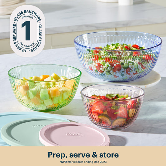 Glass bakeware bowls with food on a kitchen counter, featuring Pyrex branding.
