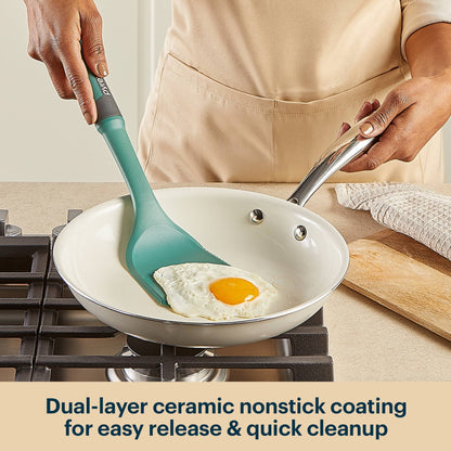 Person cooking an egg in a frying pan with a green spatula, kitchen setting.