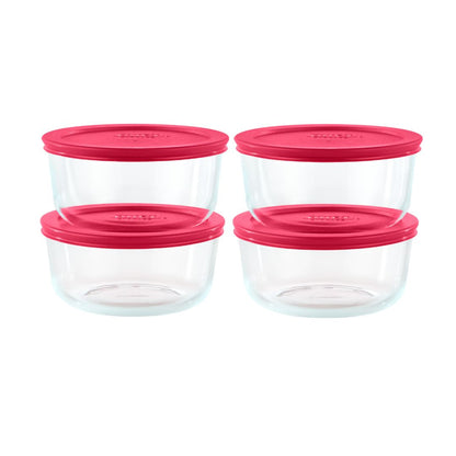 Set of four clear glass food storage containers with pink lids on a white background