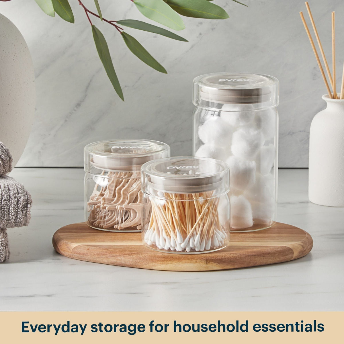 Clear jars with lids on a wooden tray against a light background