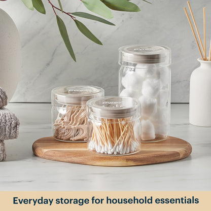 Clear jars with lids on a wooden tray against a light background